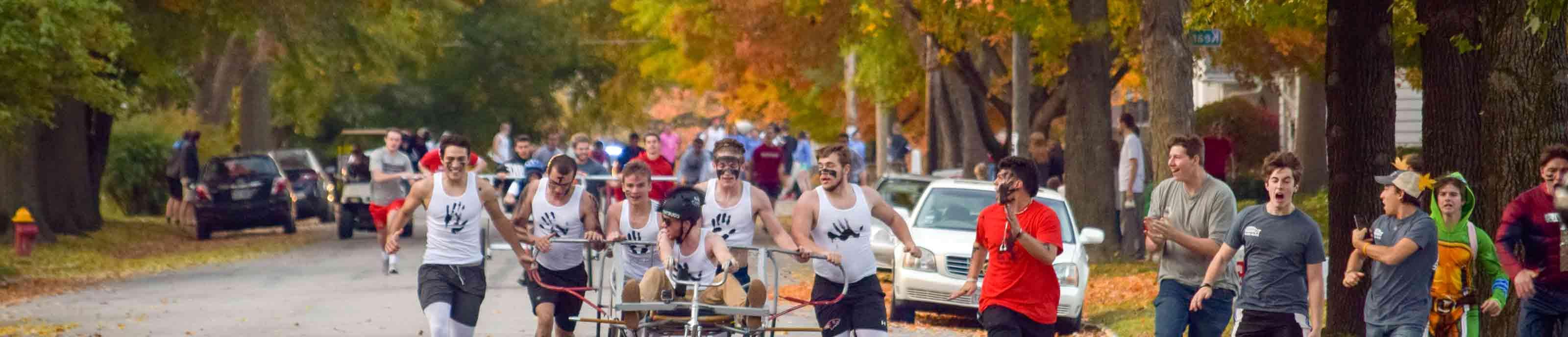 Bed racing team races by while onlookers cheer